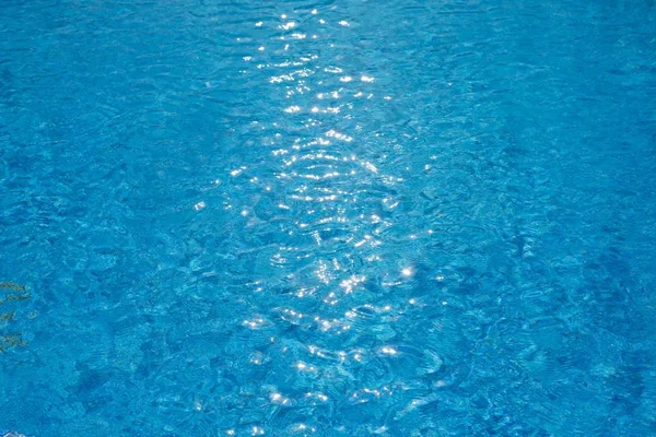 Water ripples texture in swimming pool with sunny glare — Stock Photo, Image