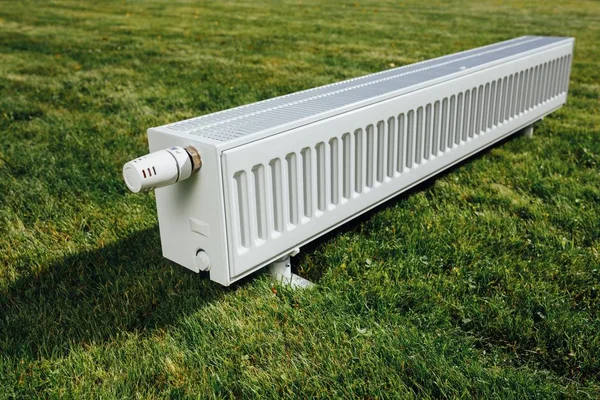 Радиатор на зеленой лужайке, концепция экологического отопления — стоковое фото