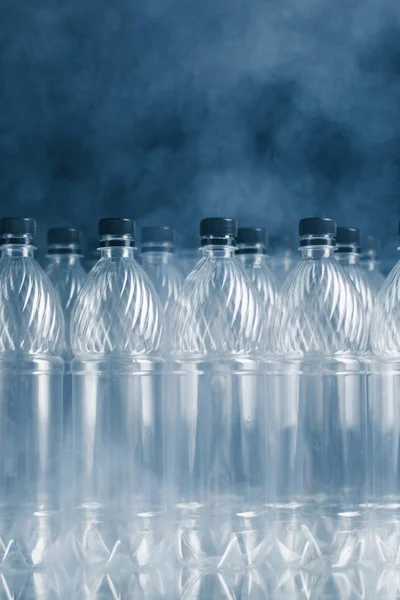 Empty plastic bottles on black background with smoke, pollution concept — Stock Photo, Image