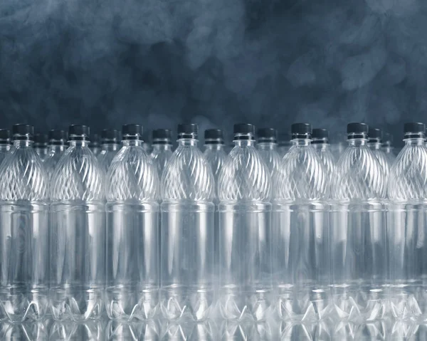 Порожні пластикові пляшки на чорному тлі з димом, концепція забруднення — стокове фото