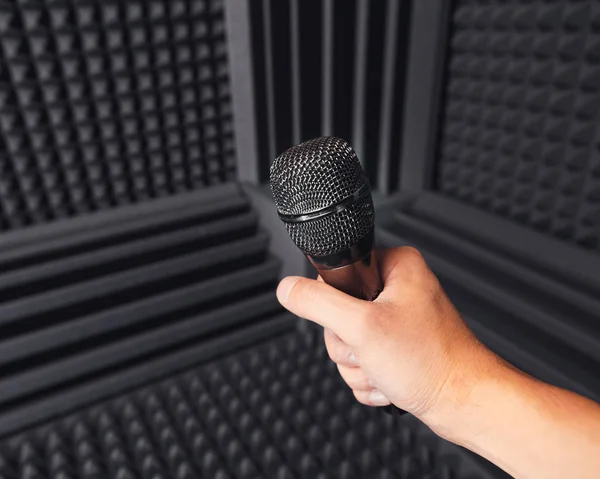 Goldenes Mikrofon in der Hand, grauer Hintergrund mit Akustikschaum im Studio — Stockfoto