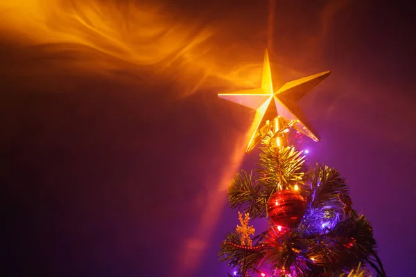 Kerstboom met feestelijke lichtjes, oranje achtergrond met rook — Stockfoto