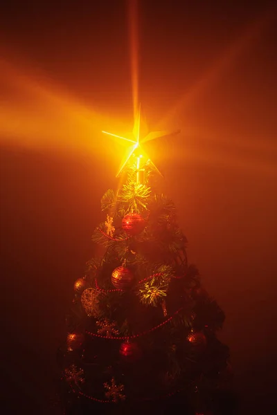 Kerstboom glanzende ster lichten, oranje achtergrond met mist — Stockfoto