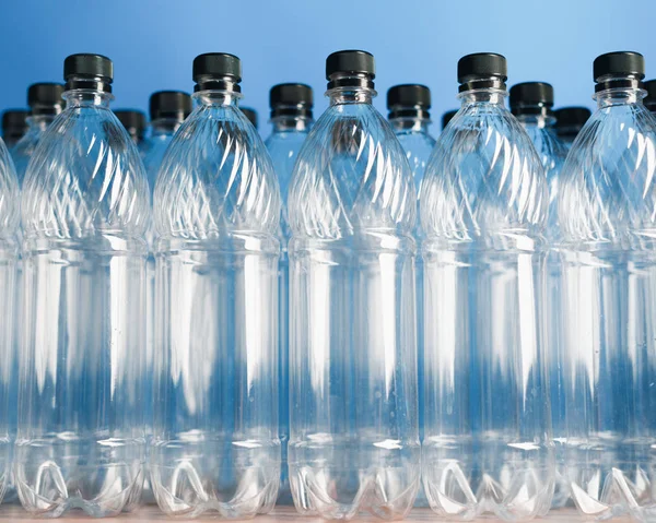 Puste plastikowe butelki na niebieskim tle — Zdjęcie stockowe