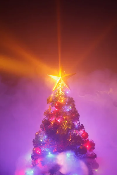 Albero di Natale con luci festive, sfondo viola con fumo — Foto Stock