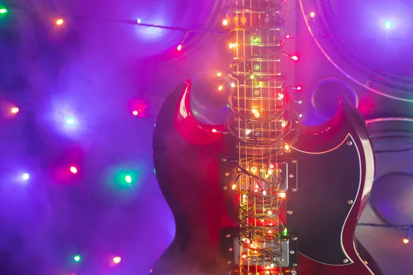 Elektrische gitaar met feestelijke kerstverlichting en muziekluidsprekers in rook — Stockfoto