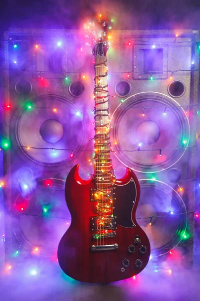 Electric guitar with festive Christmas lights and music speakers in smoke — Stock Photo, Image