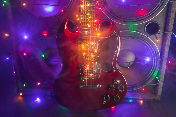 Elektromos gitár ünnepi karácsonyi fényekkel és hangszórókkal füstben — Stock Fotó