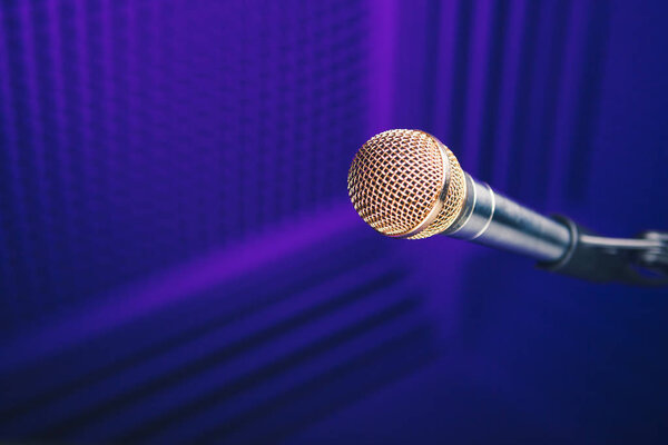 golden microphone on stand, purple background with acoustic foam in studio