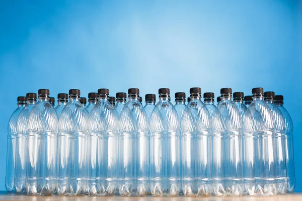 Mavi arka plan üzerinde boş plastik şişeler — Stok fotoğraf