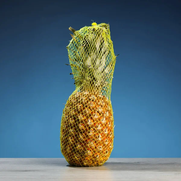 Ananas Pakowany Siatkę Transportową Niebieskie Tło — Zdjęcie stockowe