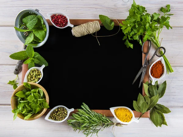 Tableau noir entouré d'herbes et d'épices — Photo