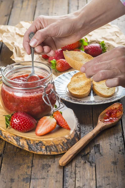 Smetar jordgubbssylt på ett rostat bröd till frukost — Stockfoto