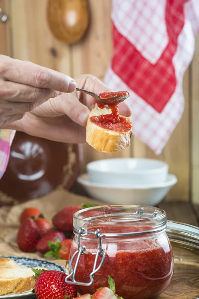 Untar mermelada de fresa en un brindis para el desayuno — Foto de Stock