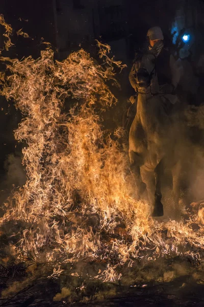 Un hombre montando su caballo saltando a través del fuego — Foto de Stock