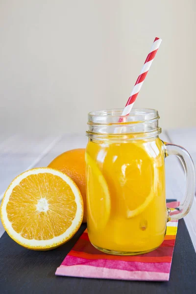 Suco de laranja em um pote de pedreiro com uma palha de bebida — Fotografia de Stock