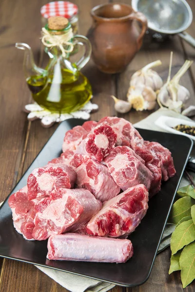 Oxtail and with olive oil and ingredients to cook it — Stock Photo, Image