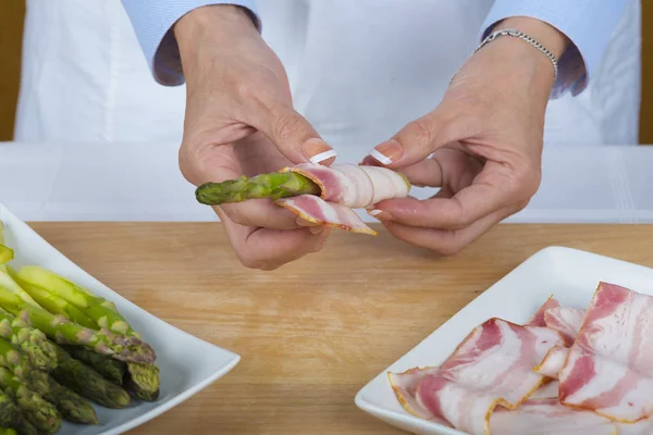 Chef che avvolge asparagi con fette di pancetta — Foto Stock