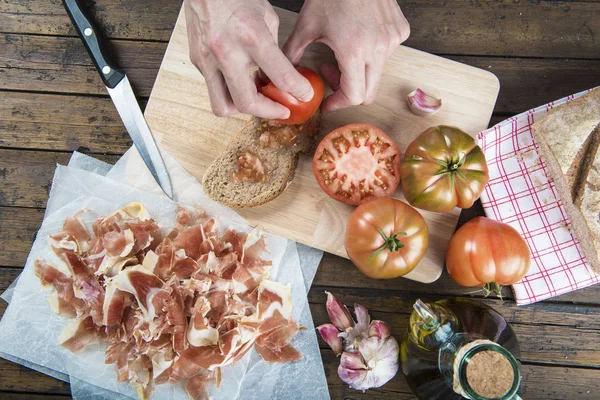 Chef esfregando tomate em uma fatia de pão — Fotografia de Stock