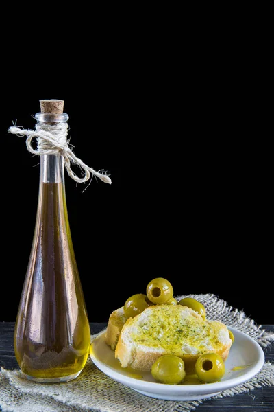 Extra virgin olive oil and bread slices with pitted green olives — Stock Photo, Image