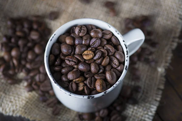 Жареные кофейные зерна в фарфоровой чашке — стоковое фото
