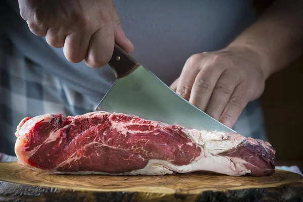 Carnicero cortando un trozo de carne con una cuchilla —  Fotos de Stock