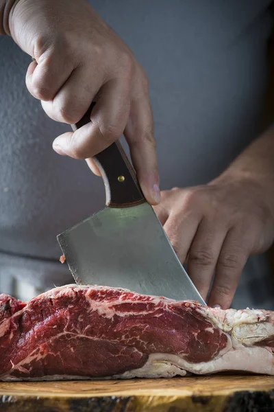 Carnicero cortando un trozo de carne con una cuchilla —  Fotos de Stock