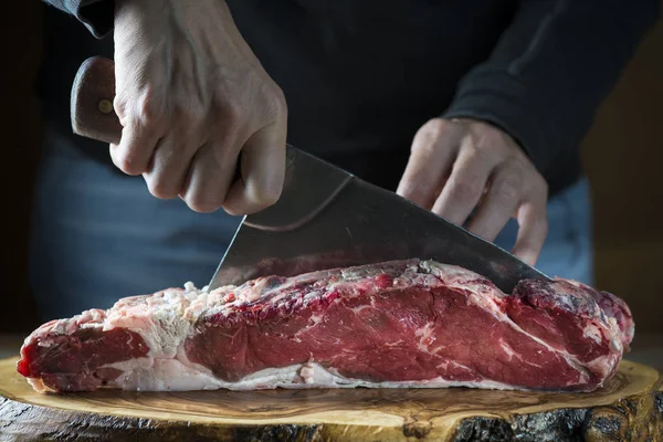 Carnicero cortando un trozo de carne con una cuchilla —  Fotos de Stock