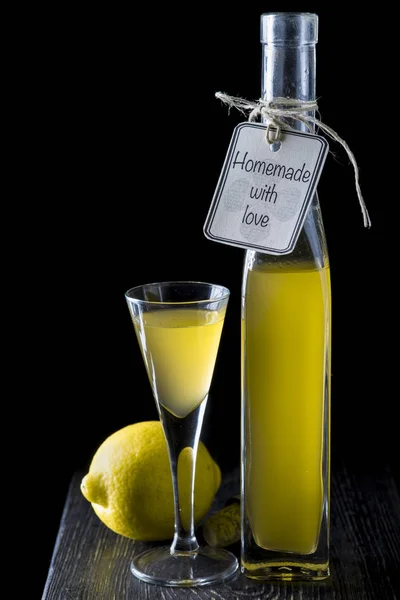 Italian limoncello in a shot glass on a black wooden background — Stock Photo, Image