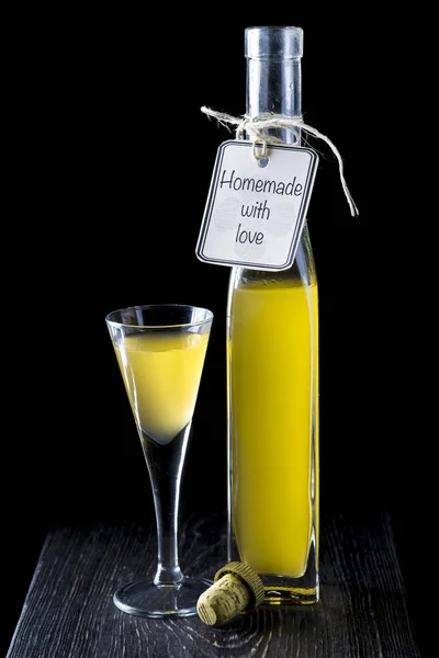 Italian limoncello in a shot glass on a black wooden background — Stock Photo, Image