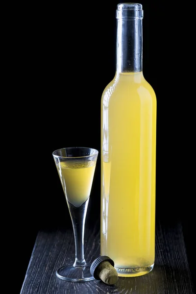 Італійський limoncello у чарку на чорному тлі дерев'яні — стокове фото