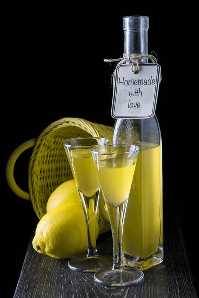 Italian limoncello in a shot glass on a black wooden background — Stock Photo, Image