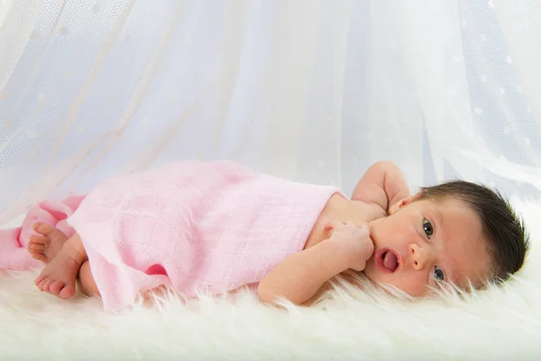 Neugeborenes Mädchen liegt glücklich und entspannt auf einer weißen Haardecke — Stockfoto