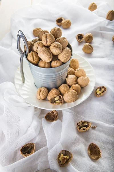 Kbelík plný ořechů s Louskáček na bílém pozadí — Stock fotografie