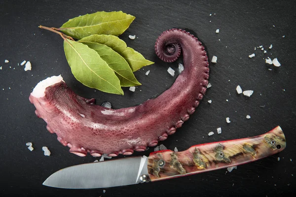 Cooked octopus over a slate plate decorated wit spices
