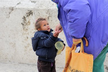Skopje, Makedonya - 18 Ekim 2016: yaşlı kadın Üsküp, Makedonya'nın başkenti şirin dilenci kız şehir merkezine para verir