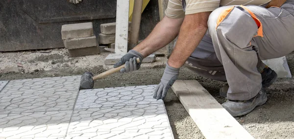 Worker tapping pavers into place with rubber mallet. Stock Picture