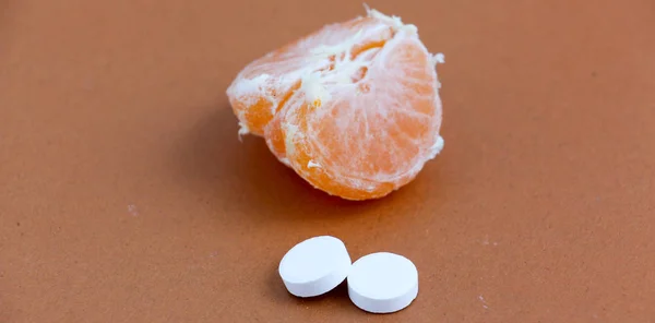 Pillole di vitamina C e fette di mandarino, vitamine naturali e artificiali, concetto sano — Foto Stock