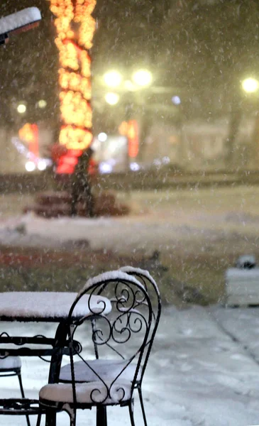 Sillas y mesa en caffe al aire libre en la noche fría nevada — Foto de Stock