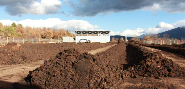 RESEN, MACEDONIA - MARCH 6, 2017: Tractor mixing manure,organic waste and soil for producing high quality compost on the producing plant near city of Resen, Macedonia