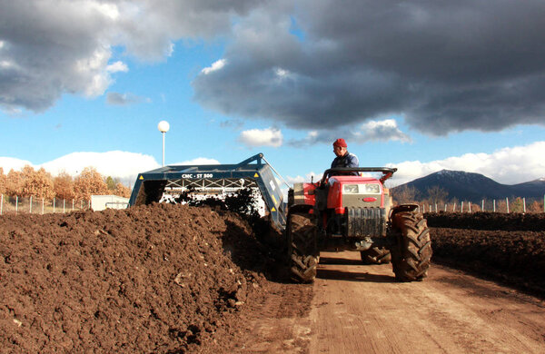 RESEN, MACEDONIA - MARCH 6, 2017: Tractor mixing manure,organic waste and soil for producing high quality compost on the producing plant near city of Resen, Macedonia