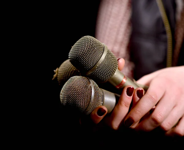 Les mains de femme tenant le microphone sale et poussiéreux sur un fond sombre — Photo