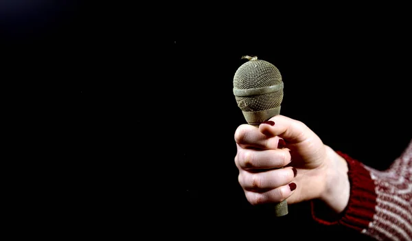 Manos de mujer sosteniendo micrófono sucio y polvoriento sobre un fondo oscuro — Foto de Stock