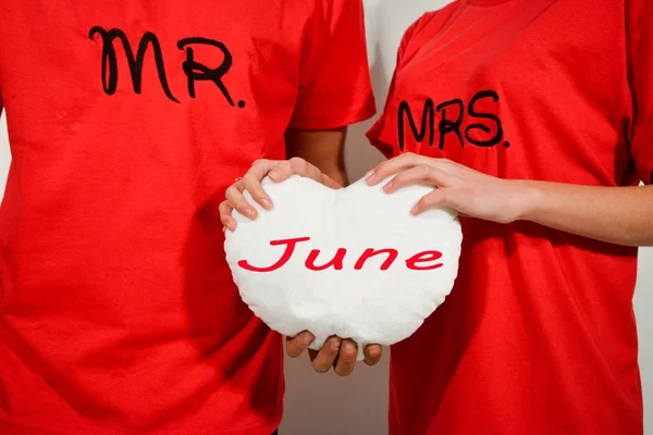 Giovane coppia in camicie rosse con cuore in tessuto bianco con testo — Foto Stock