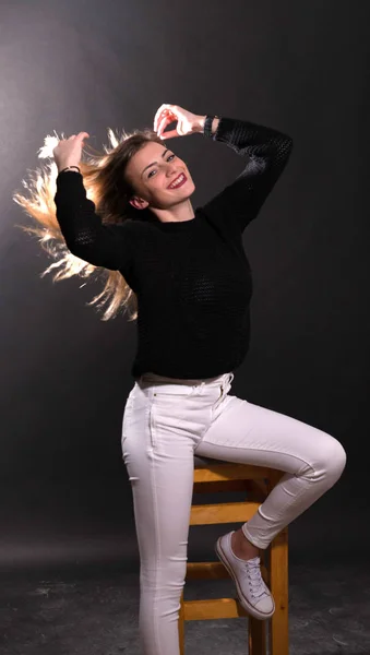 Fashion model sitting on wood chair in studio — Stock Photo, Image