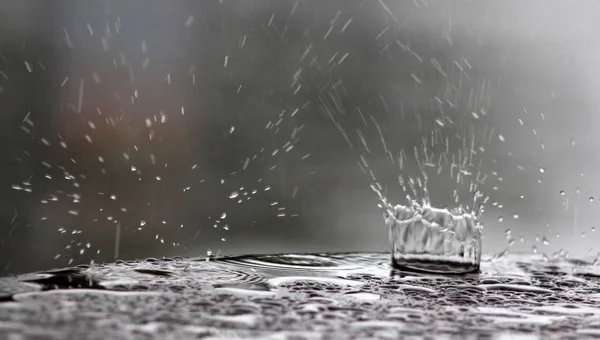 Gotas de lluvia cayendo sobre una superficie de mesa — Foto de Stock
