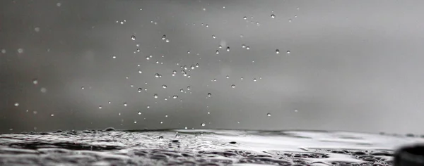 Gotas de lluvia cayendo sobre una superficie de mesa — Foto de Stock