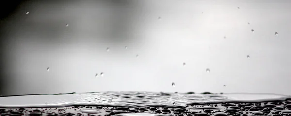 Gotas de lluvia cayendo sobre una superficie de mesa — Foto de Stock