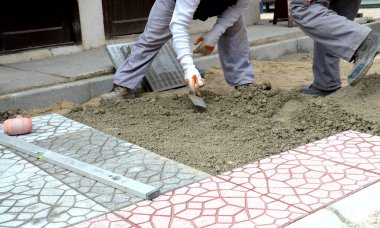 Eller dikkatle bir pozisyonda düzeltilmiş ve komisyonlu kum üste yerleştirerek yeni parke taşı döşeme bir Oluşturucu