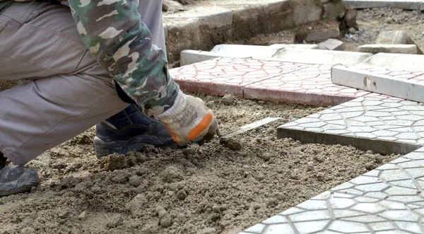 Kezében egy szóló új Burkoló kövek gondosan elhelyezése egy helyzetben egy leveled és raked homok alap építő — Stock Fotó